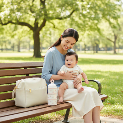 Maman bebe boite doseuse lait sur un banc au parc