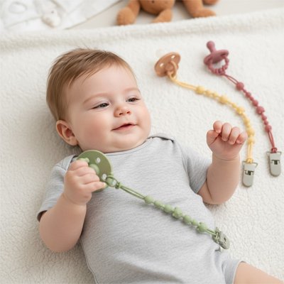 Bébé avec Attache tetine tient sa tetine 