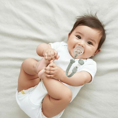 Bébé joue dans son lit Attache tetine 