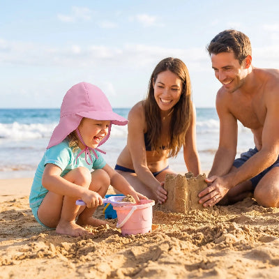 fille joue dans le sable portant chapeau bebe